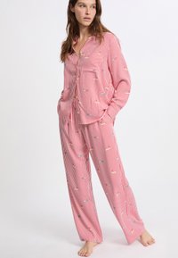 Rood-wit gestreept pyjama set bestaande uit een knoopsluiting shirt en losse broek, met kleine kleurrijke patronen overal, gemaakt van zachte stof.