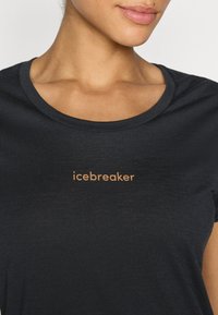Czarny t-shirt z krótkim rękawem wykonany z miękkiej tkaniny, z okrągłym dekoltem i miedzianym logo "icebreaker" na przodzie.