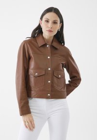 Brun läderjacka med en kragdesign, tryckknappar och två bröstfickor. Jackan har en kortad silhuett och slät textur.
