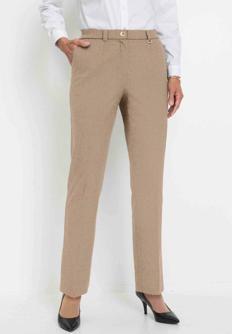 Beige op maat gemaakte broeken met een gladde textuur, voorzakken, een tailleband met gouden knopen en een recht vallend ontwerp. Draagt een paar zwarte hakken.