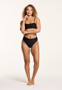 Črn bikini komplet, ki vključuje bandeau zgornji del in hlačke z visokim pasom. Gladko blago z rahlim sijajem, minimalističen dizajn in brez izrazitih vzorcev.