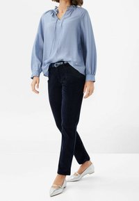 Světle modrá blůza s volánkovým výstřihem, kombinovaná s tmavě námořnickými kordovými kalhotami a stříbrnými špičatými balerínami. Hladký materiál a volný střih.