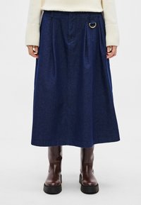 Denim midi-rok in donkerblauw met plooien en een gouden cirkelvormig metalen detail; voorzien van een gestructureerde stof en een comfortabele pasvorm.