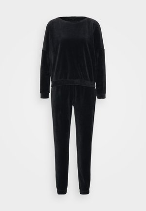 Fekete kordbársony tréningruha, amely környakú, hosszú ujjú és rugalmas mandzsettákkal rendelkezik. A felső és az alsó rész egyező bordázott textúrával készül.