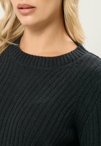 Maglione nero a coste con scollatura rotonda, caratterizzato da un motivo a maglia testurizzato e una forma aderente. Tessuto morbido con una leggera lucentezza.