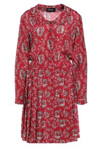 Czerwona sukienka w kwiaty z długimi rękawami, z kołnierzykiem, elastycznym pasem i marszczoną spódnicą. Ozdobiona srebrnymi akcentami w kwiecistym wzorze.