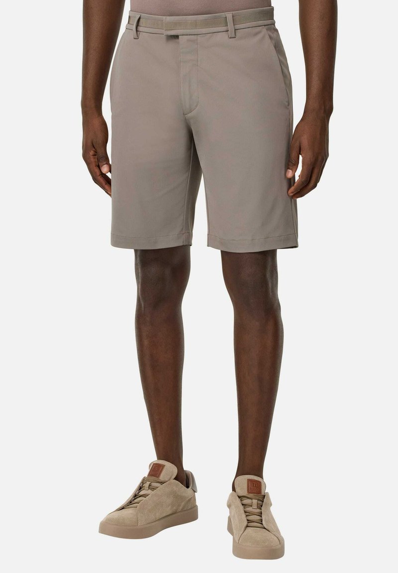 Bermuda beige da uomo realizzati in tessuto morbido, con vestibilità su misura, parte frontale liscia e tasche laterali discrete. Abbinati a sneakers beige chiare.