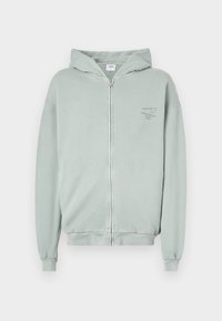 Felpa leggera verde chiaro con zip e cappuccio, polsini e orlo a coste. Presenta un piccolo logo stampato sul petto. Realizzata in tessuto morbido.
