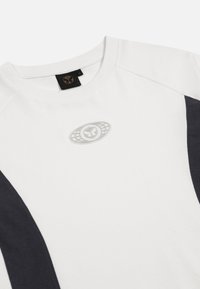 Witte T-shirt met korte mouwen en donkerblauwe zijpanelen, ronde hals en een gestructureerde logopatch in het midden. Katoenmengsel.