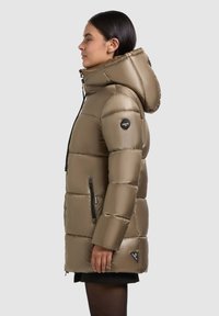 Gewatteerde parka in lichtbruin, met een stevige capuchon, ritsen op de zakken en een logo-detail op de schouder. Glad, glanzend materiaal.