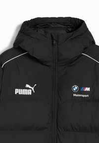 Sort polstret jakke med hætte, hvid kant og mærker: Puma på venstre bryst og BMW Motorsport på højre side.