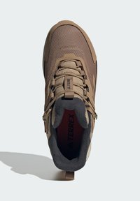 Brauner Wanderschuh mit einem Obermaterial aus Mesh, verstärkter Zehenkappe, gepolstertem Schaft und rotem Innenfutter. Mit Schlaufe an der Ferse und Schnürsenkeln.
