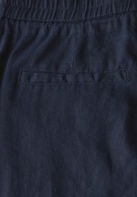 Mörkblå linnebyxor med vävd struktur, elastisk midja och en enda bakficka. Enkelt, okonstlat design för avslappnad klädsel.