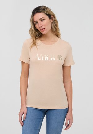 T-shirt color pesco chiaro realizzato in morbido cotone, dotato di scollo rotondo e maniche corte. Sul fronte presenta lettere dorate lucenti che formano la parola "AMOUR."