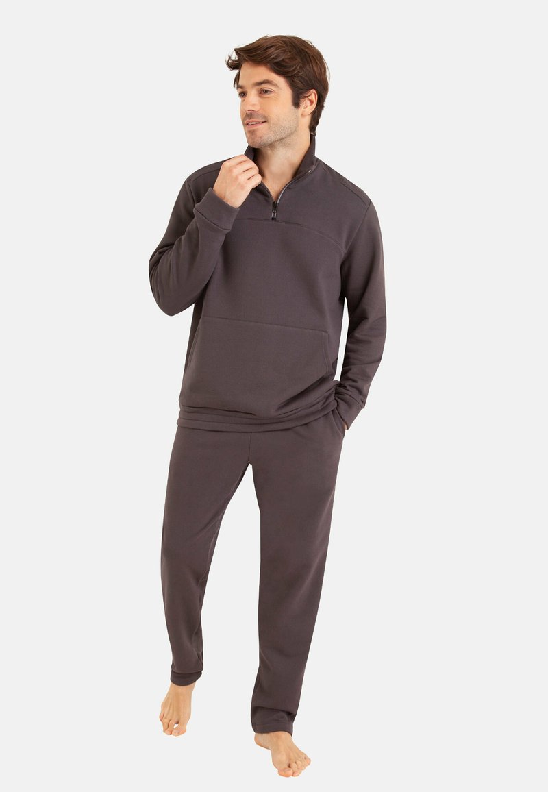Sweatshirt gris foncé avec une fermeture éclair au col, associé à un pantalon assorti. Texture douce, coupe décontractée, avec une poche avant.