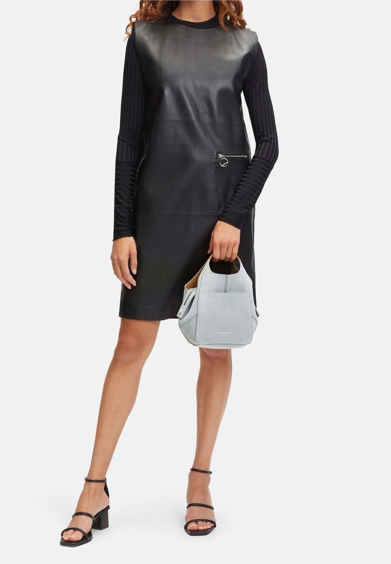 Czarna sukienka skórzana o dopasowanym kroju, z długimi prążkowanymi rękawami i boczną kieszenią na zamek. Połączona z jasnoszara zamszową torebką i czarnymi sandałami na obcasie.