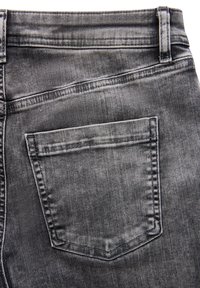 Jean en denim noir avec une poche arrière, un léger délavage et des coutures contrastantes. Tissu texturé avec une finition lisse.