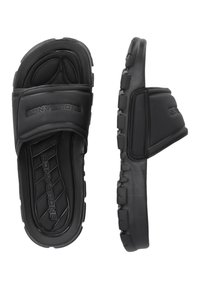 Black slide sandals with a textured rubber sole, thick upper straps featuring grooves, and branding. Open-toe design for ventilation.