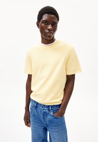 Gelbes Baumwoll-T-Shirt mit Rundhalsausschnitt, kurzen Ärmeln und einem leicht lockeren Schnitt, kombiniert mit hellblauen Jeans.