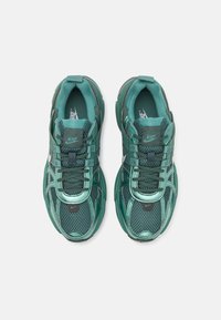 Pari vihreitä Nike-juoksukenkiä, joissa on verkkomateriaali ja synteettinen päällinen, mustat nauhat ja valkoiset Nike-logot, nähtynä ylhäältä päin.