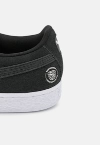 Must musta sneaker valge kummist tallaga. Omab logotäppide ja tekstureeritud kontsaga. Includes horisontaalsed õmblusaktsendid.