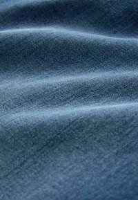 Denim w kolorze ciemnoniebieskim o gładkiej strukturze, z delikatnymi wzorami falistymi i jednolitą tkaniną w całym materiale.