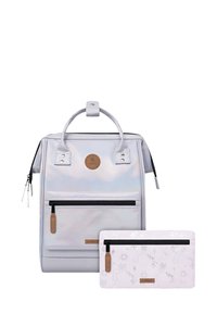 Silberne iridisierende Rucksack mit einem oberen Griff und einer Vorderzipptasche, kombiniert mit einer passenden gemusterten Tasche mit Handdesigns und einem Reißverschluss.