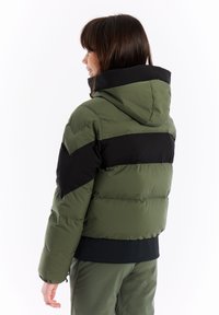 Olijfgroene pufferjas met zwarte accenten, capuchon en chevronontwerp op de schouders. Gladde textuur met een licht glanzende afwerking.