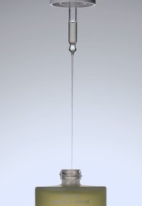 Druppelfles met een cilindrische glazen druppelaar, gevuld met een doorschijnend lichtgeel serum, tegen een neutrale achtergrond.