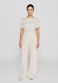 Beige short-sleeve top and wide-leg trousers. Soft, smooth fabric with a subtle sheen. Trousers feature pleats and a high-waisted design.