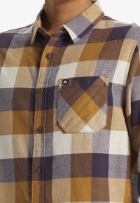 Braun-, Gold- und Weißkariertes Flanellhemd mit Button-Down-Kragen, Fronttasche und braunen Knöpfen. Weicher Stoff mit lässigem Design.