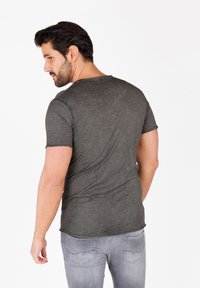 Camiseta de manga corta gris oscuro con una tela suave y texturizada. Cuello redondeado y dobladillo ligeramente curvado en la parte trasera.