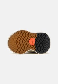 Sorel sneakersula med ett zigzag-mönster. Har bruna gummidetaljer, svarta accenter och en orange logotyp. Texturerad med hållbara material.