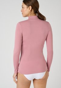 Maglietta a maniche lunghe rosa con colletto alto, realizzata in materiale morbido. Presenta un design attillato e una consistenza liscia. Adatta per essere indossata a strati.