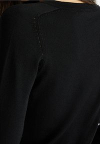 Schwarzer Strickpullover mit einer eng anliegenden Passform. Verfügt über dezente Nahtdetails an den Schultern und eine glatte Textur.
