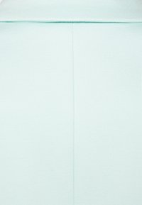 Tissu vert menthe texturé avec une surface lisse et un détail de couture visible, présenté dans un design formel et structuré.