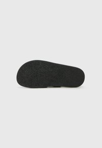 Svart skosula med en strukturerad yta och rund tån-design. Har en lätt kurva vid hälen och en slät kant runt om.