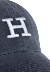 Marinblå basebollkeps tillverkad av mjukt bomullstyg, med ett stort, broderat vitt bokstav "H" på framsidan.