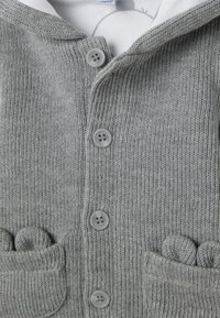 Grijze gebreide cardigan met een sjaalkraag, vijf knoopsluitingen en twee voorzakken met ronde, textuuraccenten.