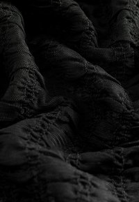 Black textured fabric with a patterned design, featuring ruffles and a soft, stretchy mesh appearance.