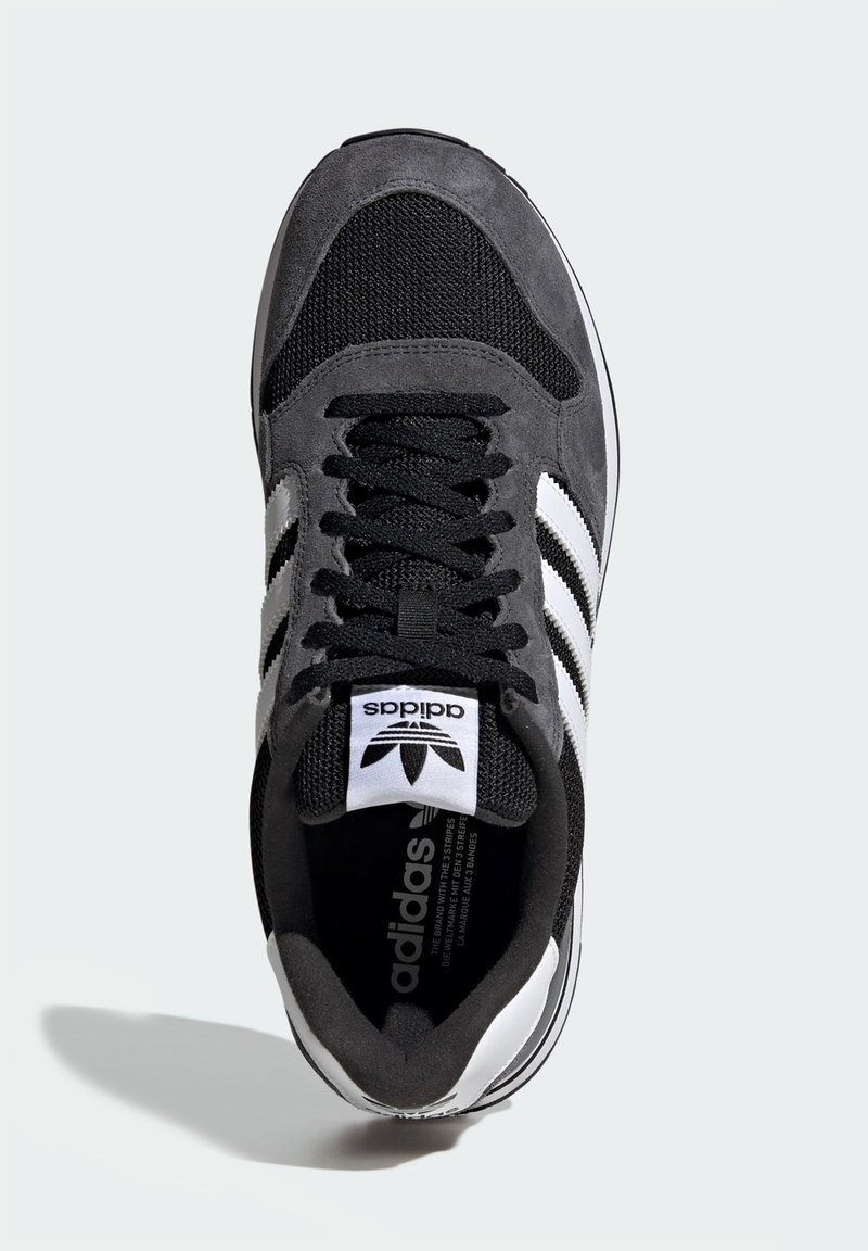 Sneaker in pelle scamosciata nera e mesh con tre strisce e logo bianchi. Presenta chiusura con lacci e colletto imbottito. Suola in gomma per una migliore trazione.