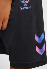 Svarta atletiska shorts tillverkade av mjukt tyg, med en färgglad logotyp och ett chevronmönster i nyanser av rosa och blått.