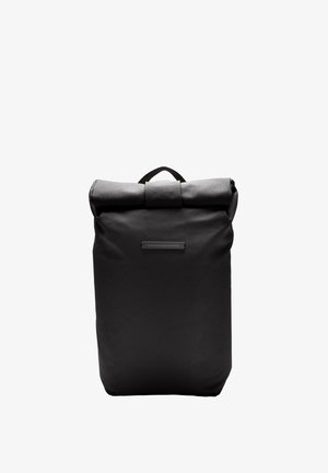 Sac à dos noir à rabat fait de tissu durable, doté d'une poignée supérieure, d'une texture lisse et d'un design minimaliste avec un petit accent en métal.