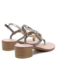 Sandali metallici grigi con tacco basso a blocco, caratterizzati da cinturini incrociati e accenti dorati. Soletta liscia con tacco testurizzato.
