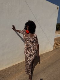 Φόρεμα maxi με λεοπάρ μοτίβο, στενής εφαρμογής, με μανίκια 3/4 και λαιμόκοψη bateau. Συνοδευμένο με ένα μεγάλο κόκκινο λουλούδι στον λαιμό.