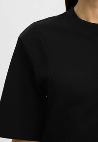 Zwarte kortekoudemouwen t-shirt van een katoenmix, met een ronde halslijn en zichtbare stiksels op de schoudernaad.