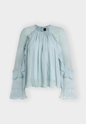 Blouse en chiffon bleu clair avec manches longues à volants, devant plissé, encolure ronde et fermeture éclair au dos.