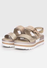 Beige Plattformsandalen mit einem goldenen metallischen Riemen, breitem Zehenriemen, verstellbarem Knöchelriemen und weißer Gummisohle mit gestreiften Akzenten.