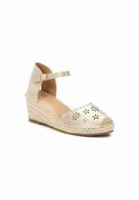 Espadrille de cuña en tono dorado con un patrón floral recortado en la puntera, un tacón de tela texturizada y una correa ajustable en el tobillo.