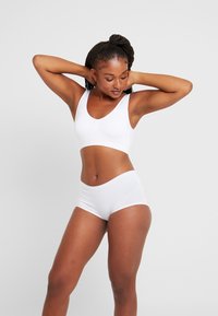 Witte naadloze bralette en bijpassende boyshorts van glad rekbaar materiaal. Heeft een brede band en een ronde halslijn voor comfort.
